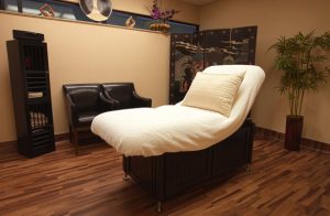 Medspa treatment room with comfortable bed and chairs and decorative furniture