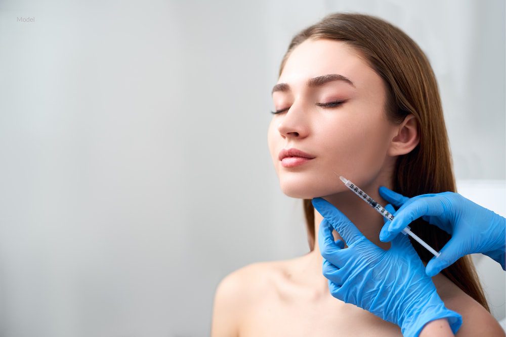 Women receiving a dermal filler injection in her jawline.