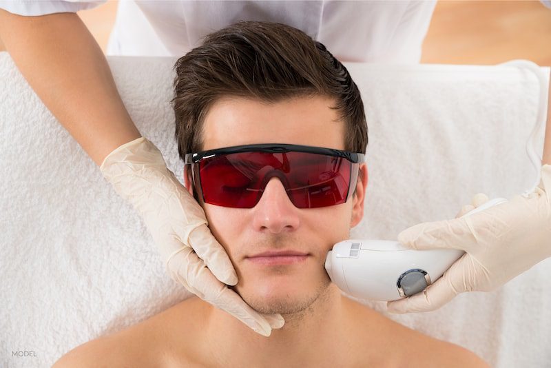 Beautician Giving Laser Treatment To Young Man Face