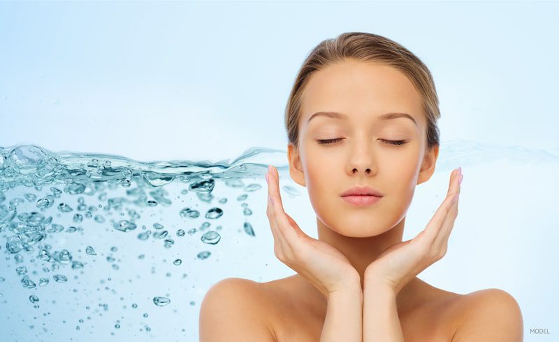 Woman's hydrated face with a backdrop of water.