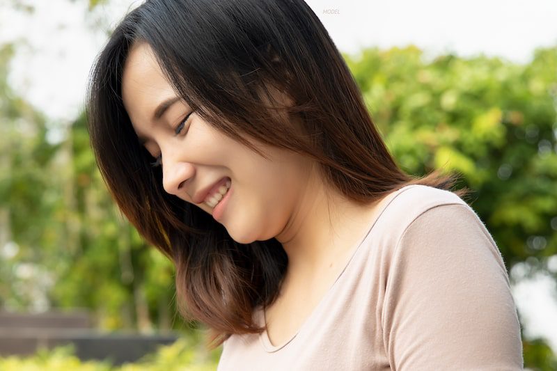 Smiling Asian women with a double chin looking down.