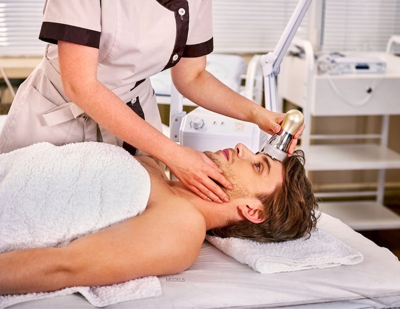 Attractive man having Ultherapy® to his forehead while he lies on a table