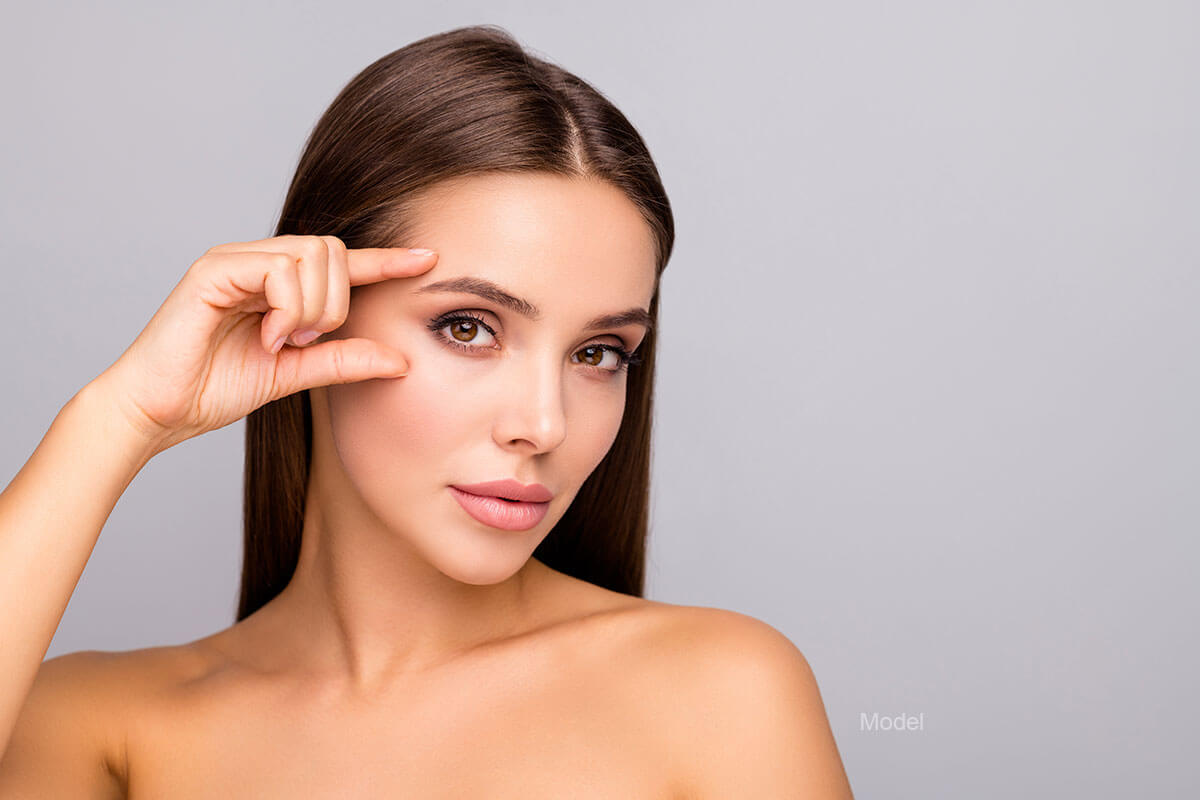 woman gestures toward her eyes