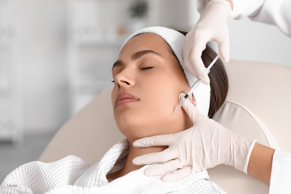 A woman in a white robe getting a facial injection